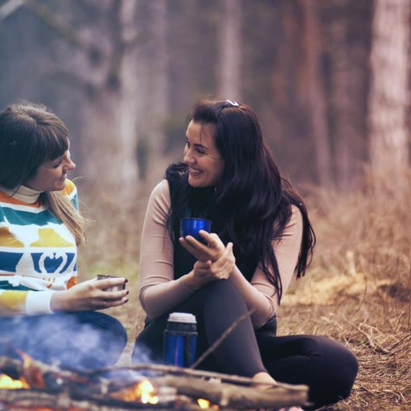 Two practitioners talking over a warm drink outdoors